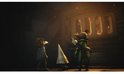 Drie kleine figuren, waaronder een met groen pakje, staan voor een grote metalen deur met verlichte ramen.
