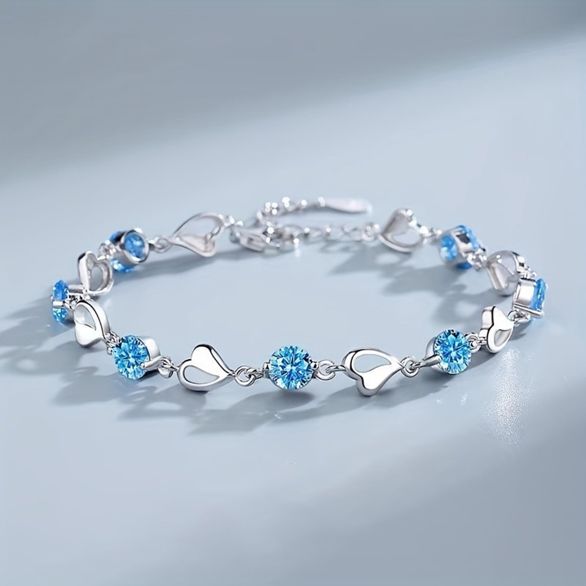 Sjika - Zilverkleurige armband met blauwe kristallen & hartjes – Luxe damesarmband – Elegant & romantisch design – Perfect cadeau voor haar