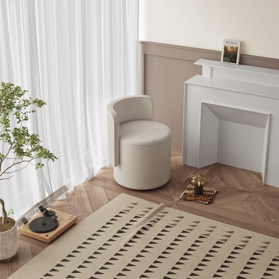 Lichtbeige, ronde kruk met een gebogen rugleuning, geplaatst in een woonkamer bij een open haard.
