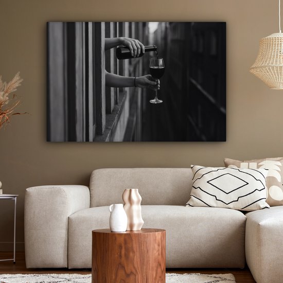 Zwart-wit canvas van handen die wijn schenken boven een beige bank met houten salontafel.