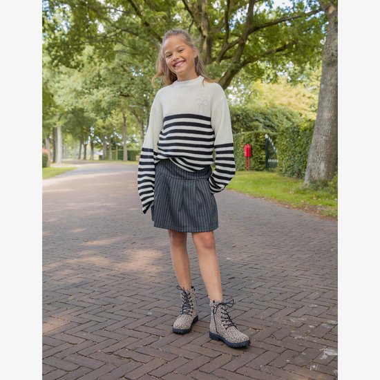 Meisje in een gestreepte rok met witte streepjes en een witte trui met zwarte strepen.