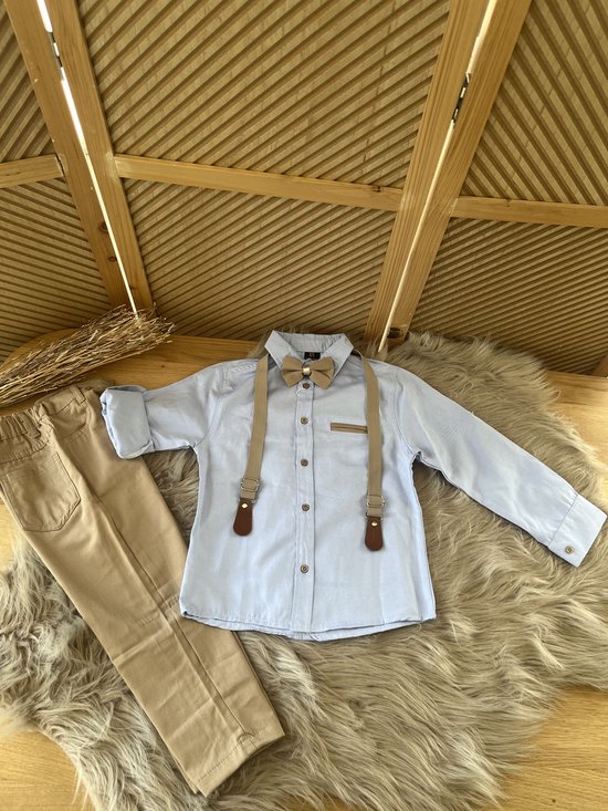 Lichtblauw overhemd met beige vlinderdas en bretels, gecombineerd met beige broek.
