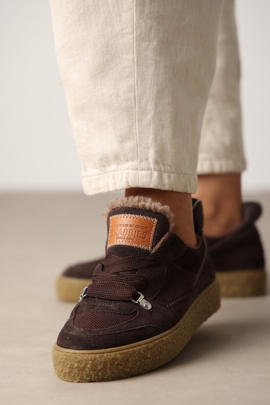 Donkerbruine suède sneakers met dikke, crèmekleurige veters en een crèmekleurige zool. De schoenen hebben een teddy voering en het "SHABBBIES" logo op de tong.