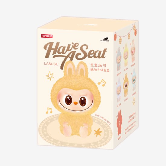 Gele Labubu met grote ogen en konijnenoren op een speelkleed, verpakt in "Have A Seat" POP MART blind box.