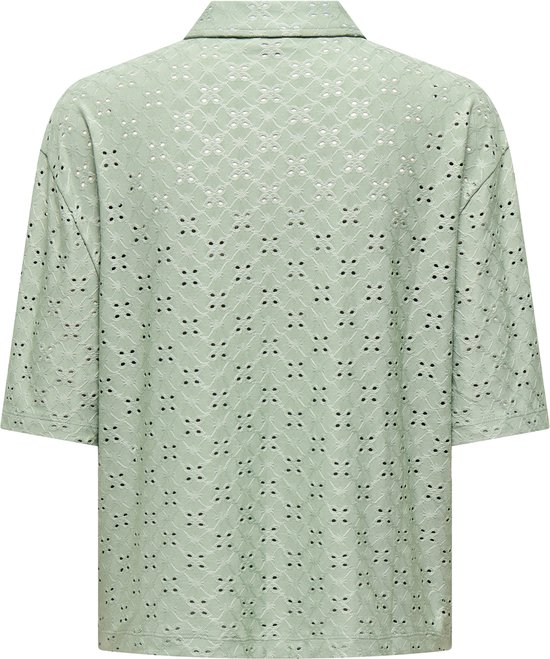 Lichtgroene blouse met korte mouwen, broderie anglaise en patroon van ruitjes en puntjes.