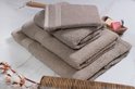 Stapel beige handdoeken van verschillende groottes, met ribbelrand. Op de voorgrond liggen gedroogde katoentakken.