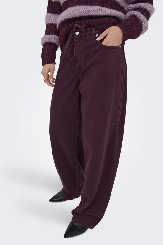 Model met paarse wijde broek met trekkoord en strik. Draagt een gestreepte trui.
