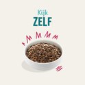 Een witte kom met hondenbrokken, met tekst 'Kijk ZELF'.