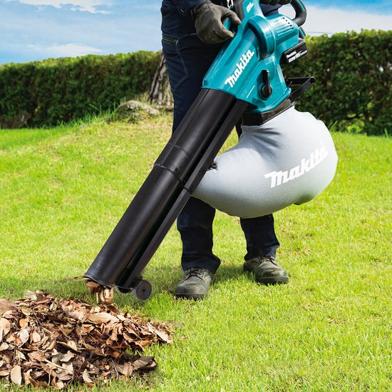 Man gebruikt turquoise Makita bladblazer in een tuin met herfstbladeren.