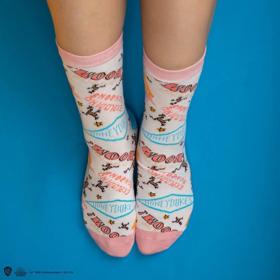 Witte sokken met prints van exploderende snoepjes en de tekst 'HONEYDUKES', gedragen op de enkels.