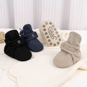 Set van vier babyslofjes in zwart, donkerblauw, beige en lichtbruin met zilverkleurige 'STEPPIES' opdruk.