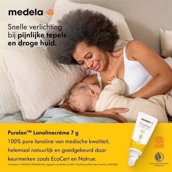Een vrouw met krullend haar voedt een baby op een bed. Een tube Medela Purelan Lanolin cream staat naast hen.