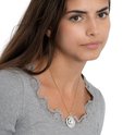 Model draagt een gouden ketting met een ronde hanger met een halve maan erop.