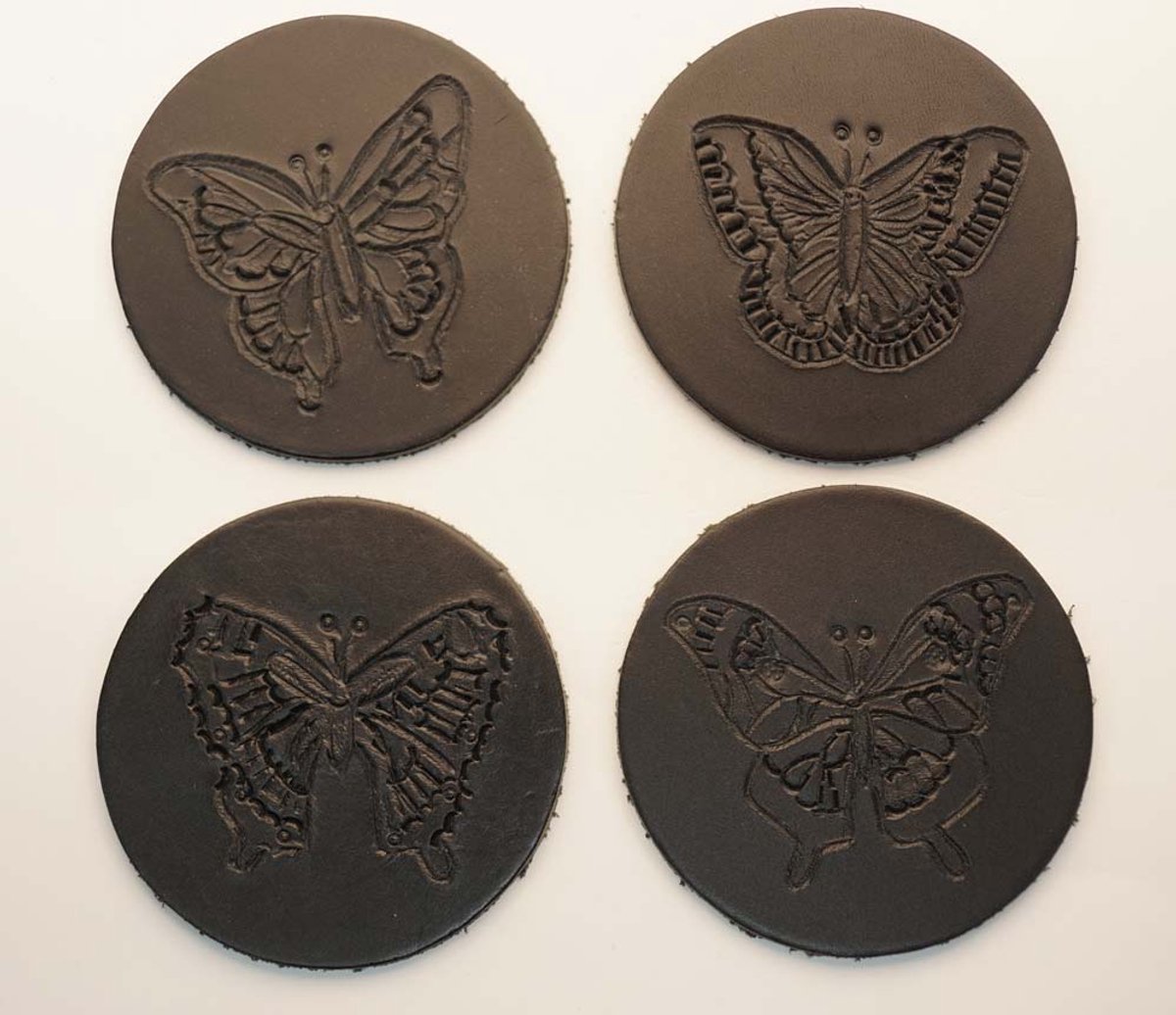 Zwarte ronde 100% leren onderzetters 4 verschillende vlinders set van 4 stuks - mooie fladderende onderzetters - fleurige onderzetters - vlinders onderzetters - butterfly onderzetters van leer - zwarte handmade onderzetters - vlindertjes onderzetters