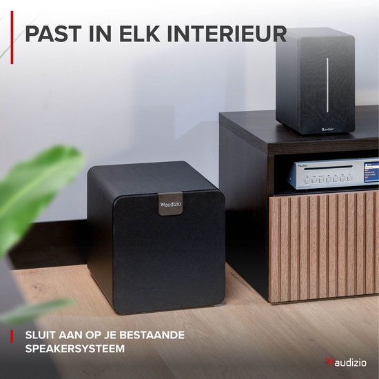 Zwarte Audizio subwoofer in een modern interieur, naast een mediakast.