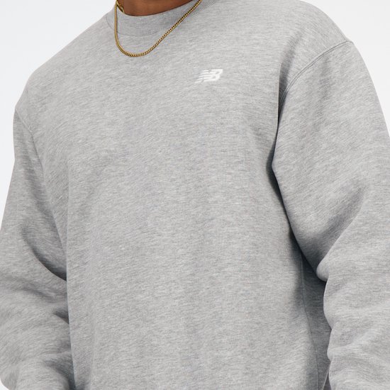 Grijze New Balance sweater met wit logo op de borst, gedragen door man.