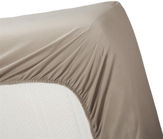Taupe hoeslaken wordt over een matras getrokken, hoek zichtbaar.