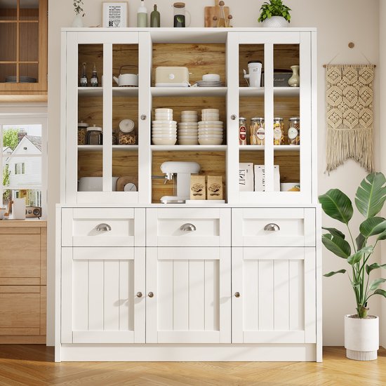 Wit dressoir met glazen deuren, houten achterwand, drie lades en drie kastdeuren eronder. Bovenin gevuld met servies en potten.