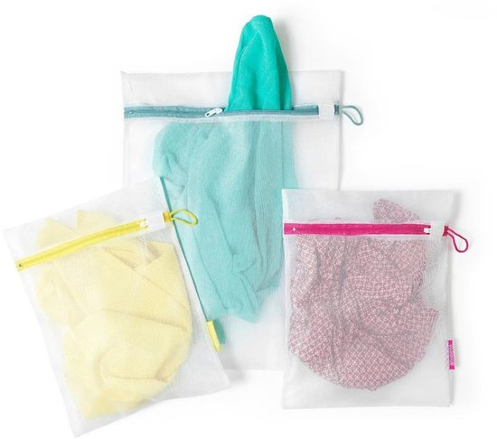 Drie witte gaaswaszakjes, de grootste met een blauwe rits en een turkooizen kledingstuk erin. De middelste met een roze rits en een roze kledingstuk erin. De kleinste met een gele rits en een geel kledingstuk erin.