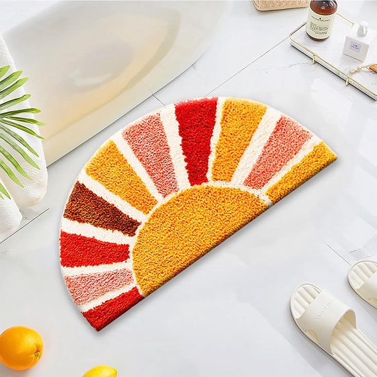 Halve cirkel badmat met zonmotief, in oranje, rood, roze en crème, naast een badkuip.