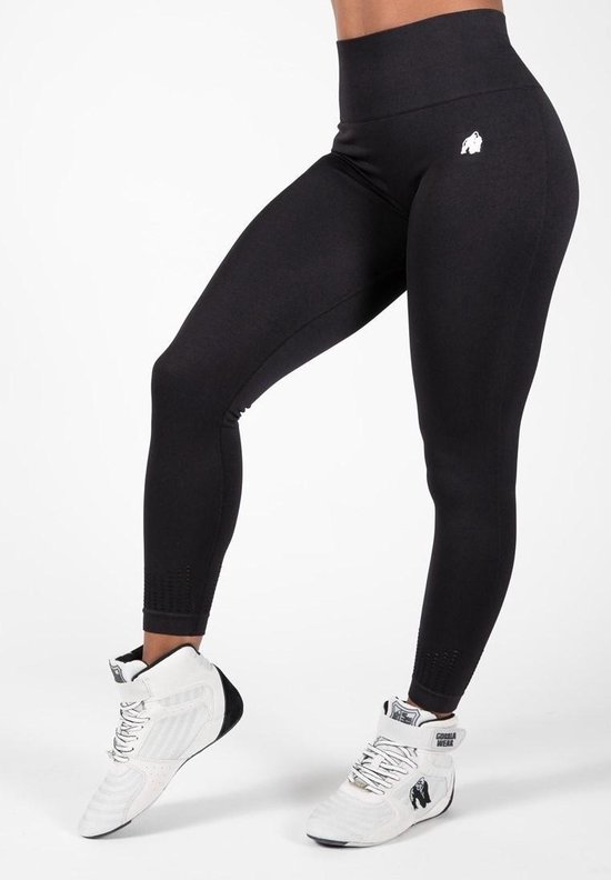 Model in zwarte, naadloze sportlegging met witte sneakers. Logo op linkerheup.