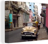 Canvas Schilderij Een Cubaanse oldtimer staat in een klein straatje in Oud Havana - 160x120 cm - Wanddecoratie XXL