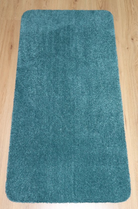 Zachte petrolkleurige badmat van 60x120cm op een houten vloer.