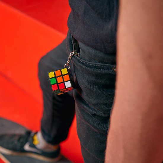 Rubik's Cube sleutelhanger aan de broek van een persoon die op een skateboard staat.