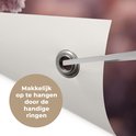 Detail van een tuinposter met een oogje en de tekst 'Makkelijk op te hangen door de handige ringen'.