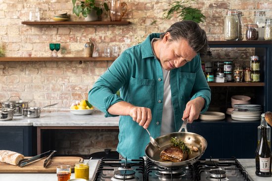 Jamie Oliver kookt een biefstuk in een pan met een takje rozemarijn.