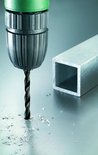 Tête de perceuse fore dans un tube métallique, des copeaux de métal volent.