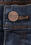 Close-up van een koperen spijkerbroekknoop met de tekst 'Wrangler Authentics'.