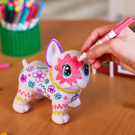 Een hand kleurt de witte Franse Bulldog Washimal in met een roze stift. De hond is al versierd met bloemen, sterren en zigzaggrenzen.