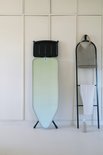 Brabantia strijkplank met groen-blauwe gradiënt hoes in een kamer met handdoekenrek.