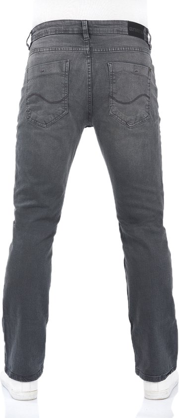 Achterkant van een man in grijze bootcut jeans met witte sneakers.