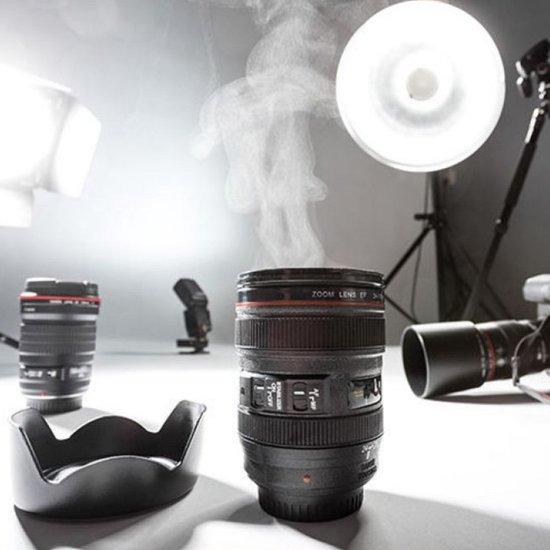 Zwarte cameralens beker met stoom, in een studio met camera's, lenzen en flitsers.