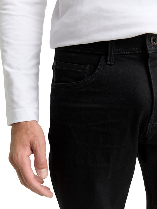 Detail van de zakken van een zwarte jeans, gedragen door een man.