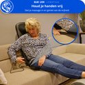 Vrouw met blonde haren zit op een bank en gebruikt het massagekussen, met een detailfoto van de controller.