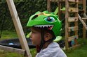 Groene kinderfietshelm met dino-design, grote ogen en scherpe tanden.