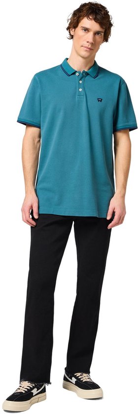 Man in blauwe polo met kraag en zwarte jeans.