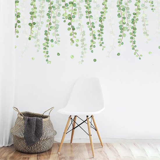 Chaise blanche et panier avec couverture grise devant un mur avec autocollant mural de lianes d'eucalyptus retombantes.