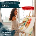Vrouw met gebreide trui schildert op een schildersezel. Tekst "HOOGWAARDIGE EZEL" en "Perfect voor beginners".