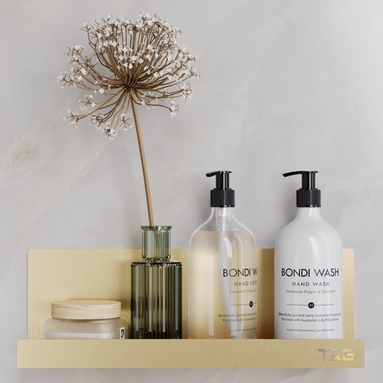 Gouden wandplank met Bondi Wash handzeep, handlotion en een decoratieve plant.