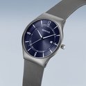 Grijs BERING horloge met blauwe wijzerplaat, cijfers 12, 3, 6, 9 en mesh band.