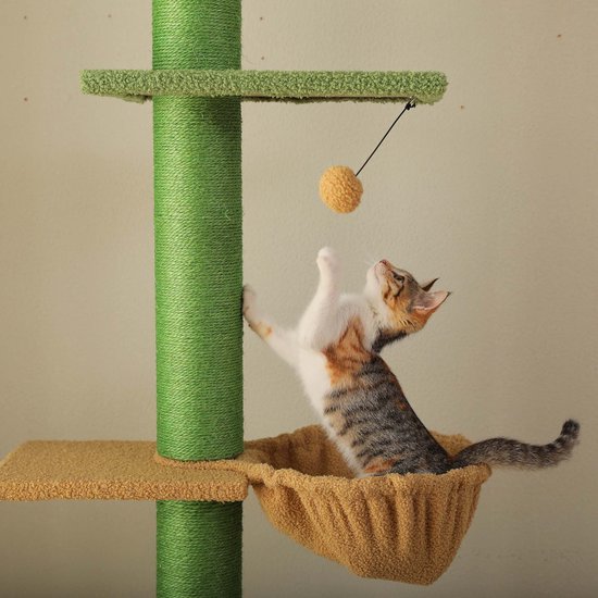 Kitten in een bruin mandje, speelt met een gele bal aan een touwtje, op een groene krabpaal.