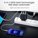 Zwarte Siltcon 65W GaN oplader aangesloten op een wit stekkerblok, met een telefoon, tablet en laptop die tegelijkertijd worden opgeladen.