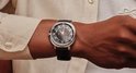 Close-up van een smartwatch om een pols, met zwarte band en zilverkleurige rand. Zwarte wijzerplaat.
