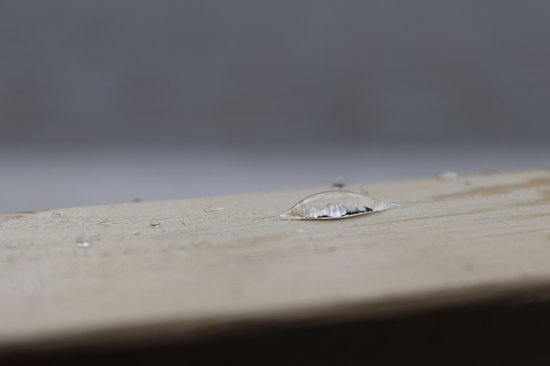Waterdruppels rollen af van een houten oppervlak.