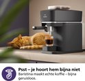 Zwarte Philips Baristina volautomatische espressomachine naast een slapende kat.