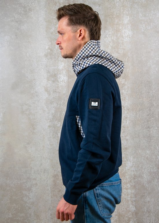 Man draagt donkerblauwe hoodie met geblokte kraag, profiel zichtbaar.